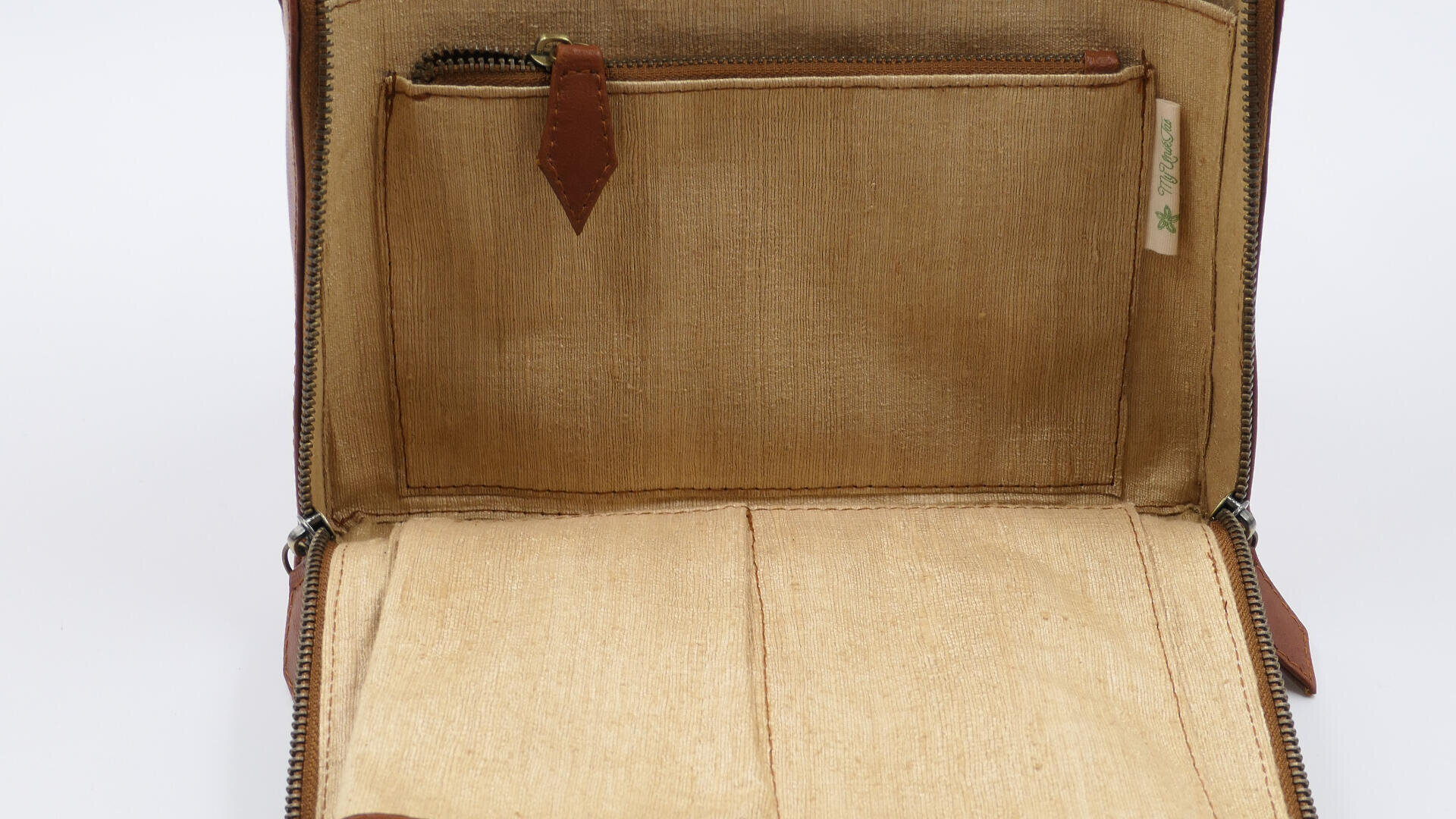 Offene Brieftasche aus hellbraunem Stoff mit einer Reißverschlusstasche und einfachen Fächern, leer auf weißem Hintergrund.