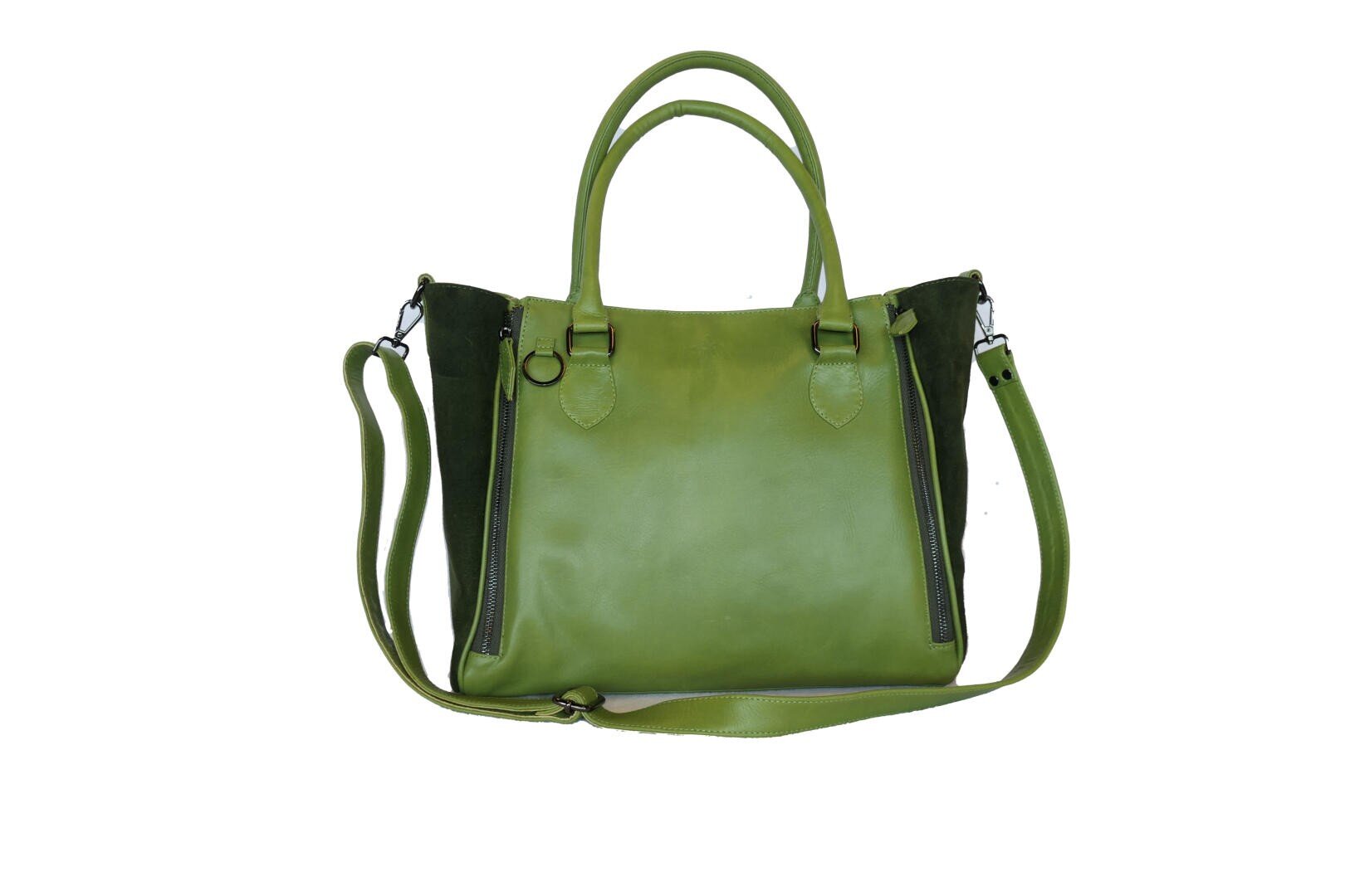Eine grüne Lederhandtasche mit zwei Griffen, einem abnehmbaren Schulterriemen und schwarzen Seitenteilen auf weißem Hintergrund. Die Tasche hat vertikale Reißverschlüsse auf jeder Seite der Vorderseite.