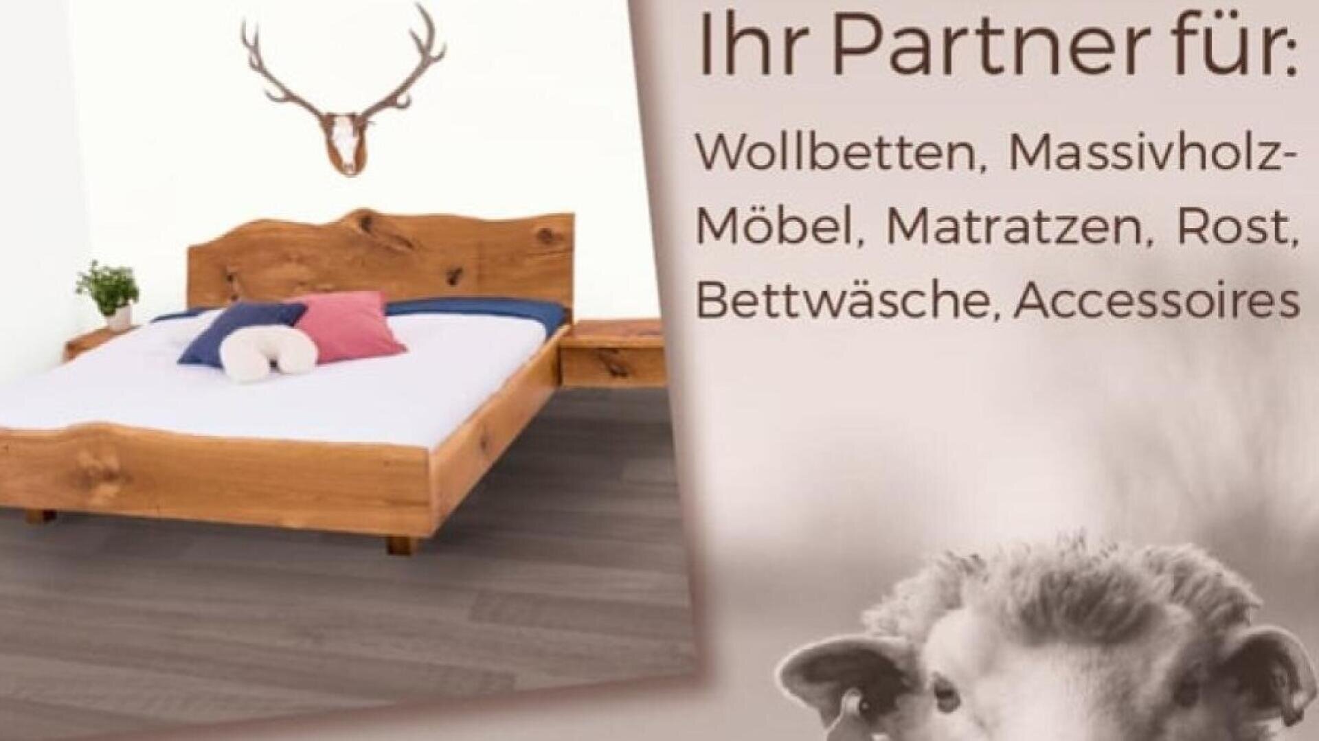 Ein Holzbett mit weißem und rosafarbenem Bettzeug steht in einem Raum mit Geweihen an der Wand; der deutsche Text listet Produkte wie Bettgestelle, Matratzen und Zubehör auf. In der rechten unteren Ecke ist ein Schafsgesicht abgebildet.