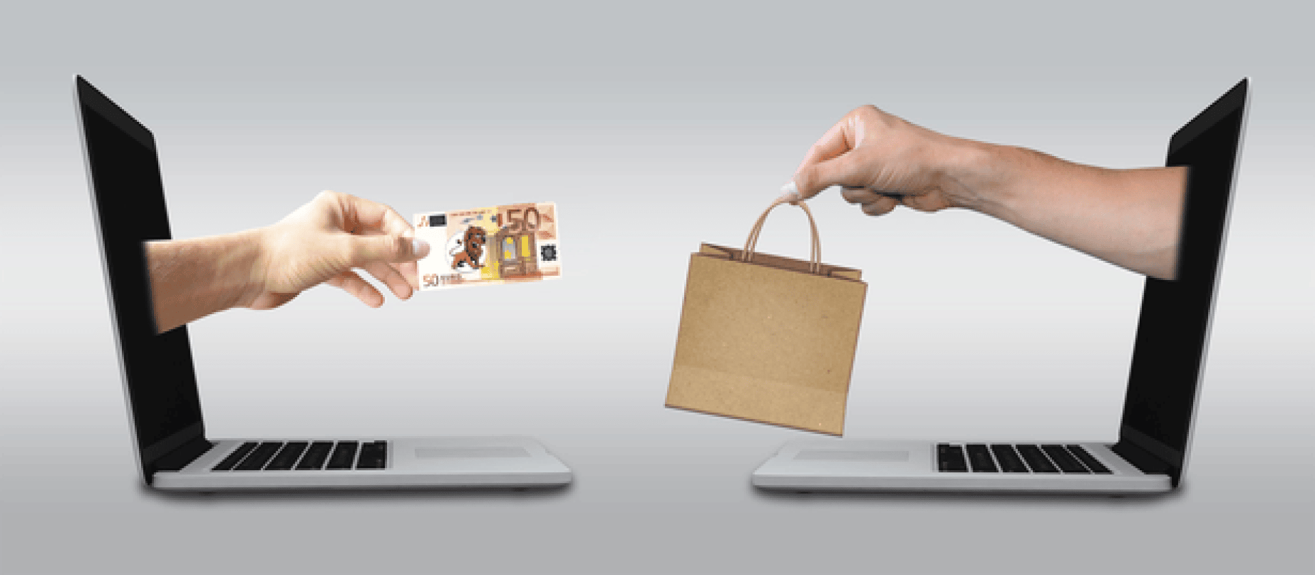 Eine Hand streckt einen 50-Euro-Schein aus einem Laptop-Bildschirm heraus, während eine andere Hand eine kleine Einkaufstasche aus Papier aus einem zweiten Laptop herausstreckt, was für Online-Shopping oder E-Commerce steht.