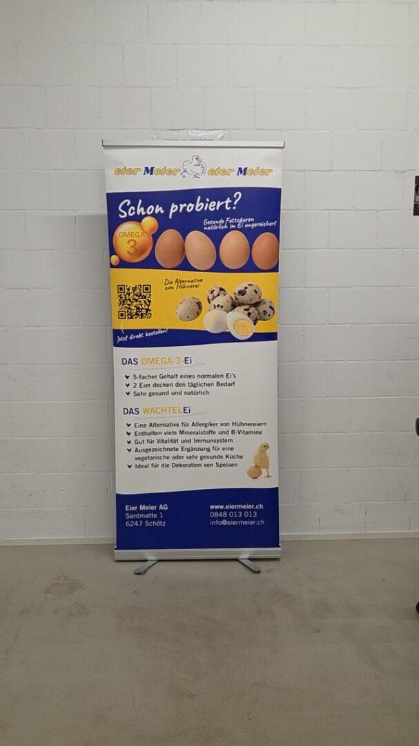 Ein vertikales Banner mit Bildern von Eiern, einem aufgeschlagenen Ei und einem Küken, das mit einem deutschen Text für Eier wirbt. Das Banner hat QR-Codes, Kontaktinformationen und ein blaues und weißes Farbschema und steht vor einer weißen Wand.