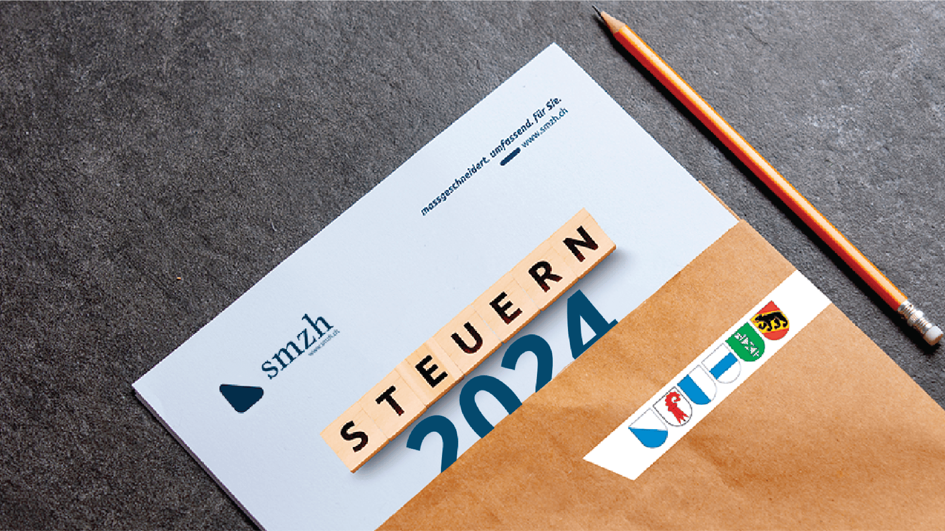 Ein brauner Umschlag mit einem teilweise sichtbaren Dokument mit der Aufschrift "2024" und "STEUERN" (Steuern auf Deutsch), das mit Buchstabenkacheln geschrieben ist. Ein Bleistift und einige Aufkleber sind ebenfalls auf einer dunklen Oberfläche zu sehen.