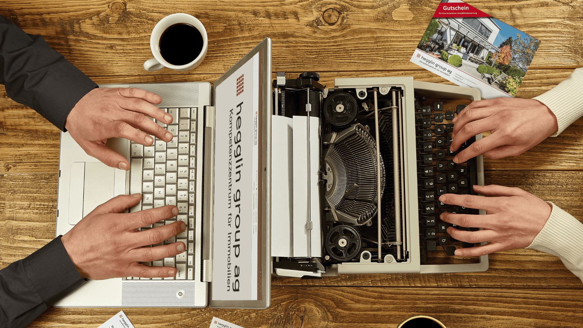 Zwei Personen tippen auf einem Laptop und einer Schreibmaschine, die nebeneinander auf einem Holztisch stehen, mit Kaffeetassen und Papieren in der Nähe, um den Kontrast zwischen alter und moderner Technologie hervorzuheben.
