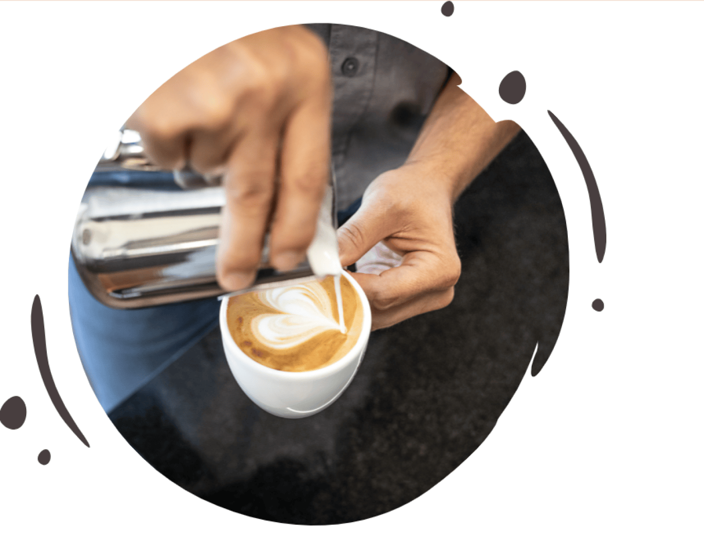 Eine Person gießt gedämpfte Milch aus einem Metallkrug ein, wodurch ein Latte-Art-Herzmuster auf der Oberfläche einer Kaffeetasse entsteht. Der Hintergrund ist unscharf und konzentriert sich auf die Hände und die Kaffeetasse.
