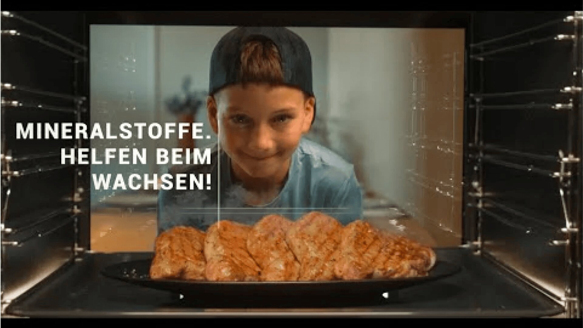 Ein lächelnder Junge in einem blauen Hemd und einer Mütze schaut in einen Ofen auf ein Tablett mit gekochten Hühnerbrüsten. Der Text auf dem Bild lautet: "MINERALSTOFFE. HILF BEIM WACHSEN!".