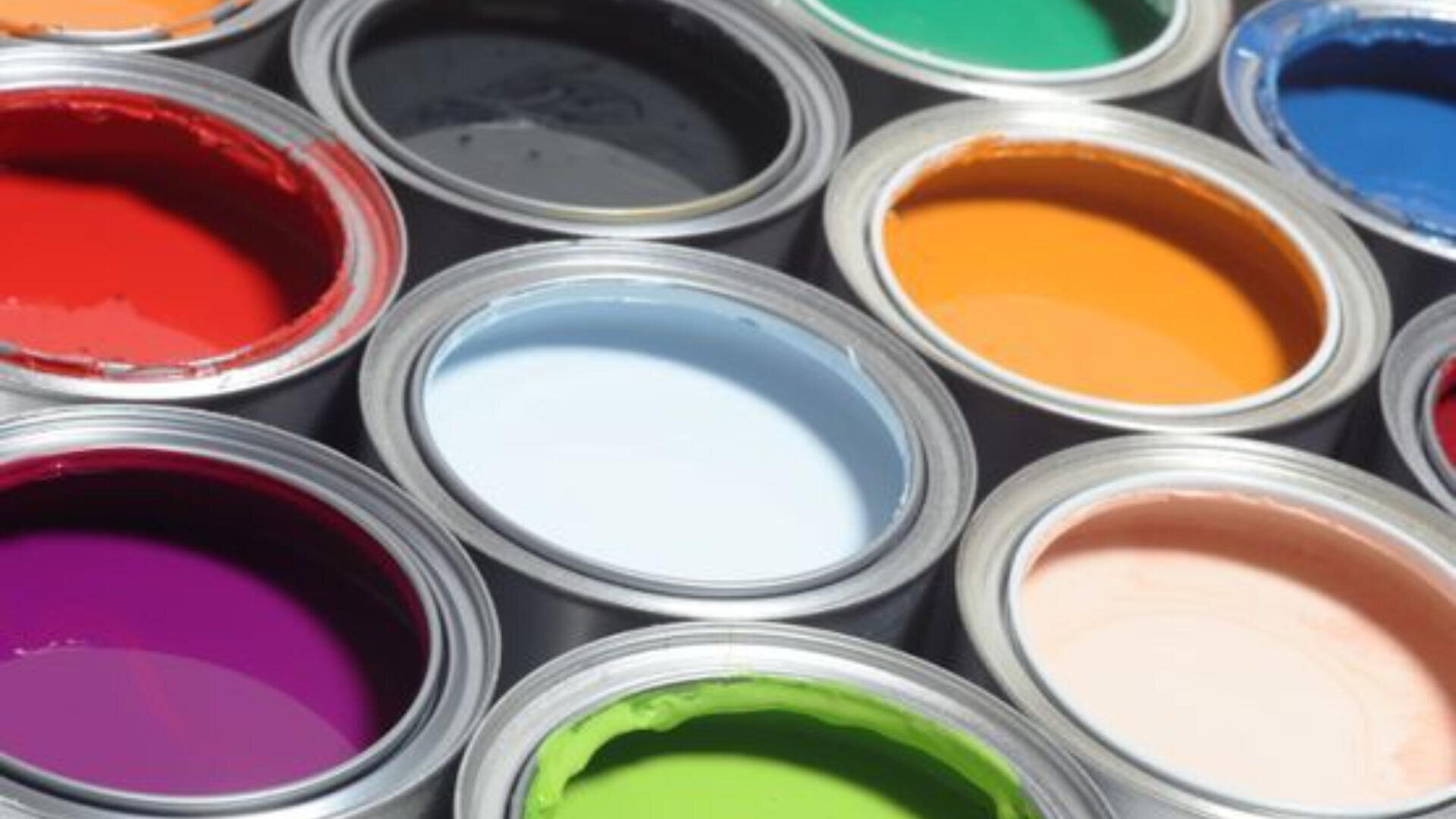 Offene Farbdosen, die dicht nebeneinander angeordnet sind und jeweils eine andere leuchtende Farbe zeigen, darunter Rot, Orange, Blau, Grün, Lila, Rosa, Schwarz und Weiß.