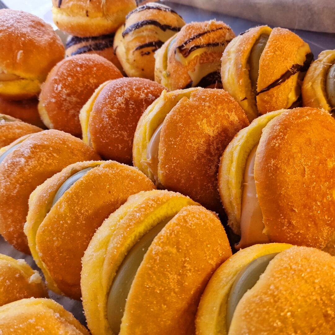 Dicht an dicht reihen sich runde, gezuckerte, mit pastellfarbener Creme gefüllte und zum Teil mit Schokoladenlinien überzogene Gebäckstücke aneinander.
