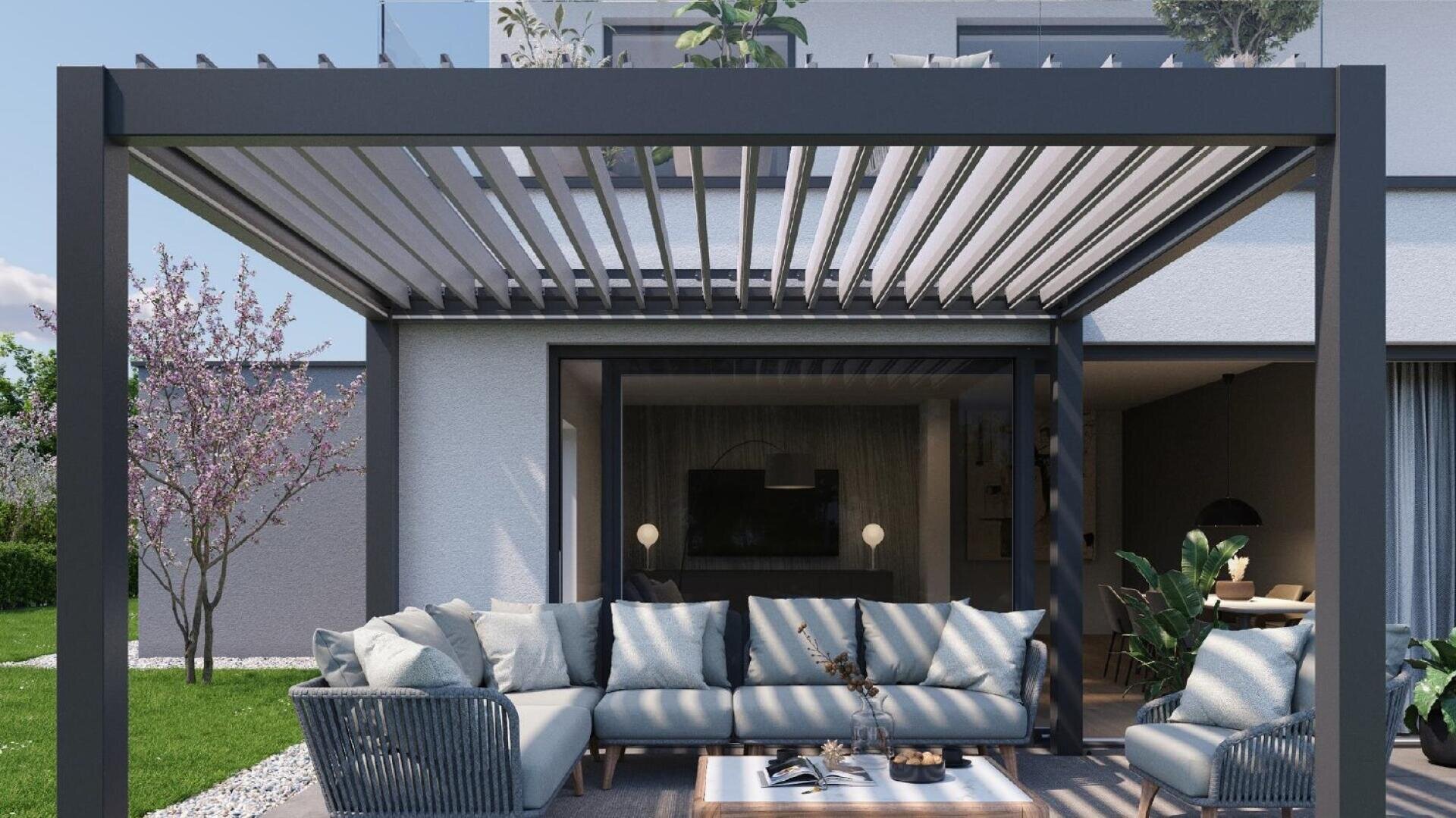 Eine moderne Außenterrasse mit einer grauen Pergola, hellblauen gepolsterten Sektionssofas, einem Couchtisch und Pflanzen vor einem modernen weißen Haus mit großen Glastüren und üppiger Bepflanzung.